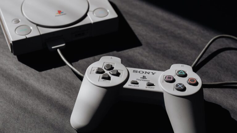 photo of play station game console and remote controller
