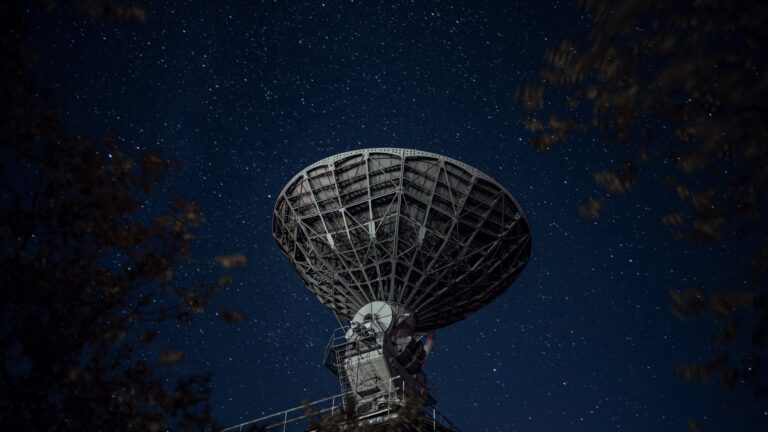radio telescope against sky with stars