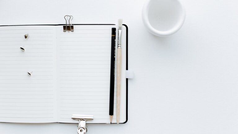 opened notebook with pencil and paintbrush