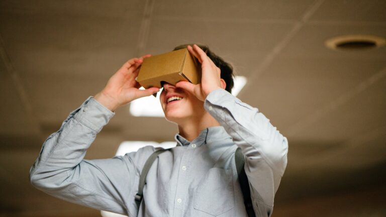 man in grey dress shirt using brown cardboard vr glasses