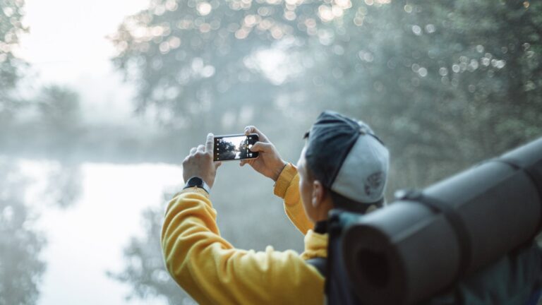 person in yellow jacket taking photo of white clouds