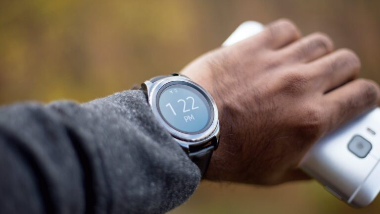 silver colored smartwatch with black strap on person s wrist